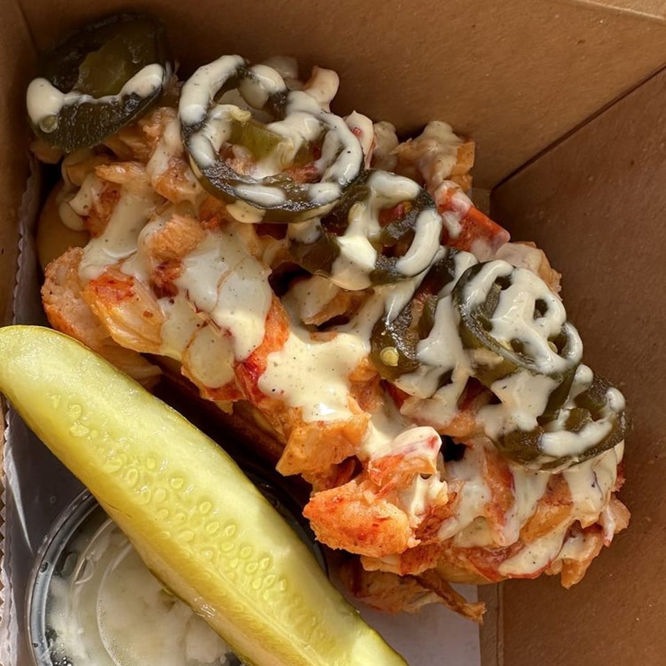 A Boca Lobster Roll with creamy sauce and jalapeños, served with a pickle spear.