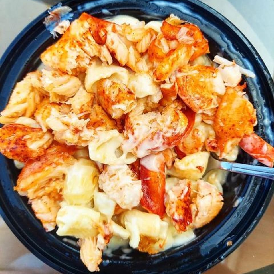 Close-up of a black bowl filled with creamy lobster mac and cheese from The Boca Lobster Roll Company.